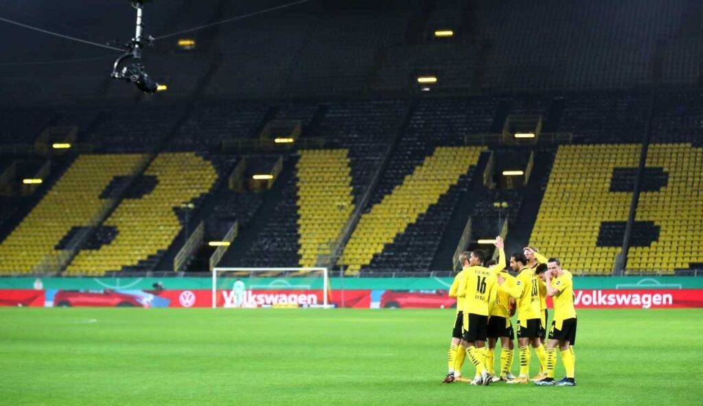 I giocatori del Borussia esultano in uno stadio tristemente vuoto