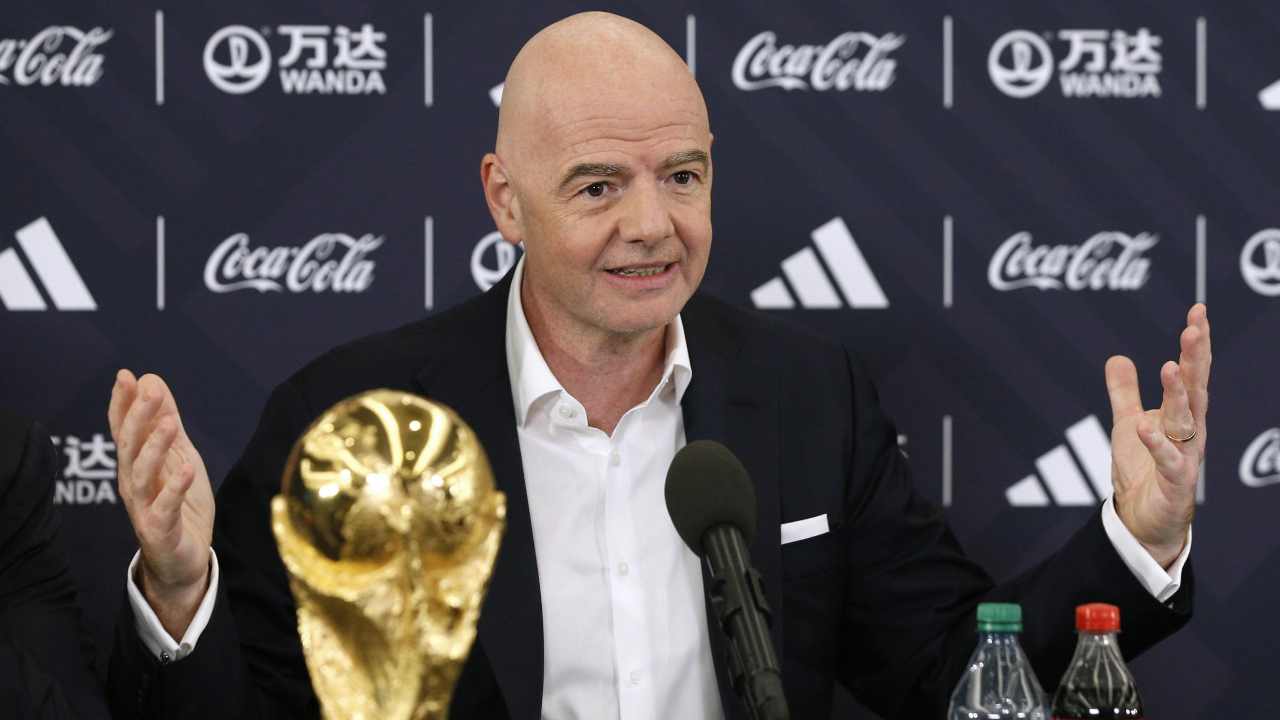 Infantino allarga le braccia con la coppa dei Mondiali davanti 