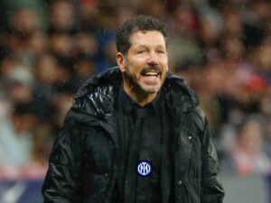 Diego Simeone in giacca e cravatta nera e uno logo dell'Inter appuntato su
