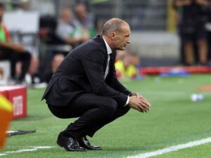 Massimiliano Allegri accovacciato e pensieroso davanti alla panchina del Milan